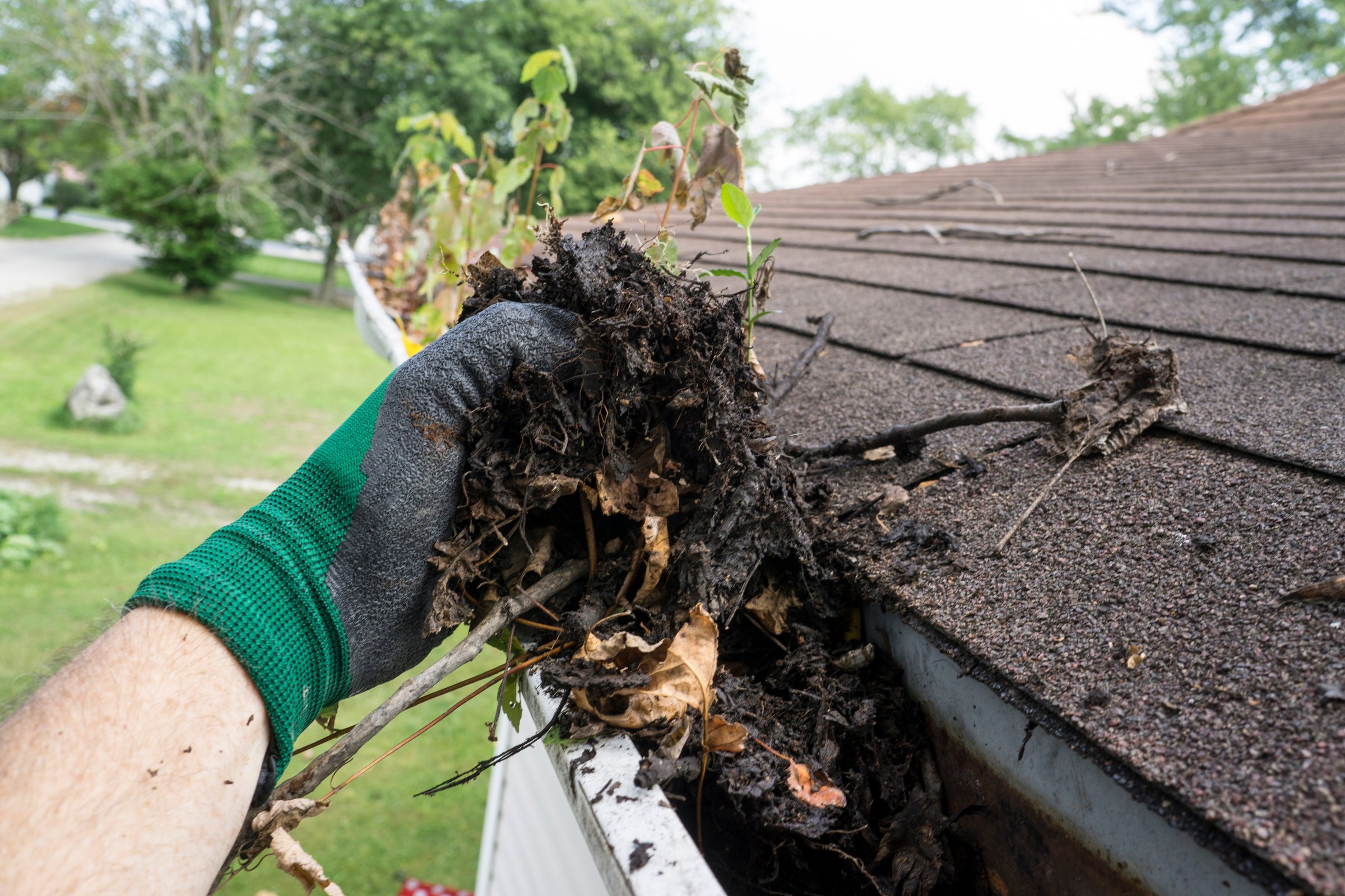 Worker Cleaning Gutters For A Customer